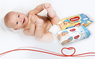 Bebè sdraiato che ride con le salviette Huggies® Pure